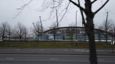 MANCHESTER, UK - 2020: Manchester's Etihad Stadium with trees, road and cars