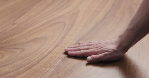 Slow motion man hand touches black walnut dining table surface