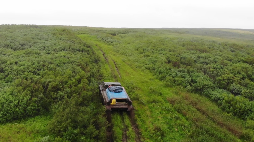 Aerial view of a military vehicle in a field on a cloudy day, view of the lake and field, Russia, Nenets Autonomous district