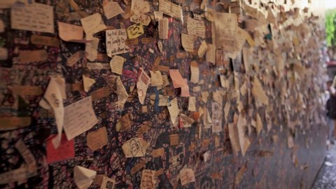 VERONA, ITALY - JUNE 2019: Pan shot left to right with little cards with a loving dedication on the wall of Juliet's house at Romeo and Juliet wall of love, in Verona June 2019