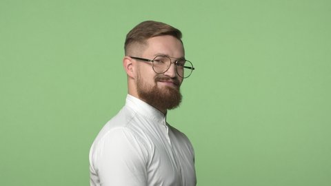 Slow-motion handsome male entrepreneur, confident man in glasses, made new haircut barber, stand back to the camera, turn around and hinting with eyes, glancing as if have interesting news, smiling