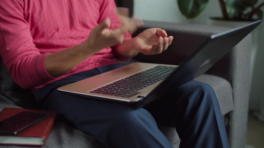Close-up of hands of hearing impaired man communicating with sign language during video conference online using laptop on sofa. Deaf-mute male with laptop pc online messaging using sign language. | Shutterstock HD Video #1044019834
