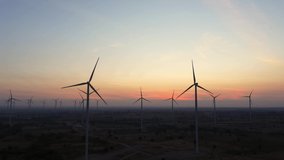 Aerial view of Wind turbines of save Energy save world in video 4k format. aerial shot on sunset. drone footage wind turbines at sunrise with beautiful clouds. Global warming concept and green energy.