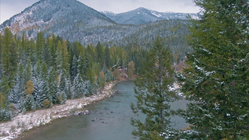 Aerial flying over Mountains and trees covered in snow,& The Middle Fork Flathead River in West Glacier, Glacier National Park, Montana, USA 