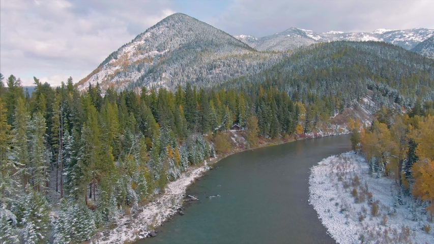 Aerial flying over Mountains and trees covered in snow,& The Middle Fork Flathead River in West Glacier, Glacier National Park, Montana, USA 