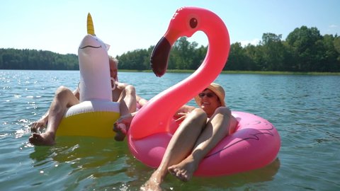 Elderly couple floating on inflatable flamingo and unicorn. Funny active pensioners happy together enjoying summer vacation on the beach in Europe, laughing, playing the fool, splashing water