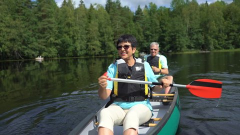 Elderly couple canoeing on a forest lake in Finland. Active retirees enjoy outdoor sports. Sportive elderly people having fun at the nature.