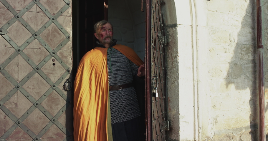 Portrait of historical chieftain in mantle comes out from fortress and looks up. Slowly in 4K