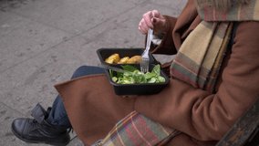 woman eating a salad on city bench