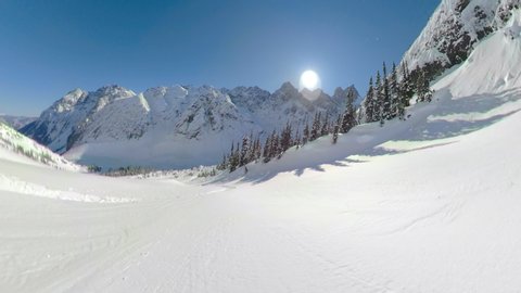 POV: Awesome first person shot of snowboarding off piste in the gorgeous Canadian mountains. Shredding the fresh powder snow during a heliboarding trip in British Columbia. Beautiful wintry landscape.