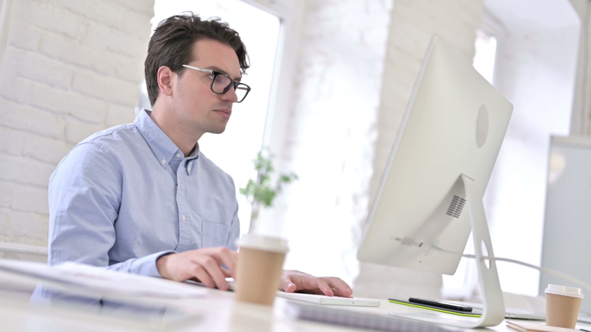 Focused Working Young Man Drinking Coffee and using Desktop