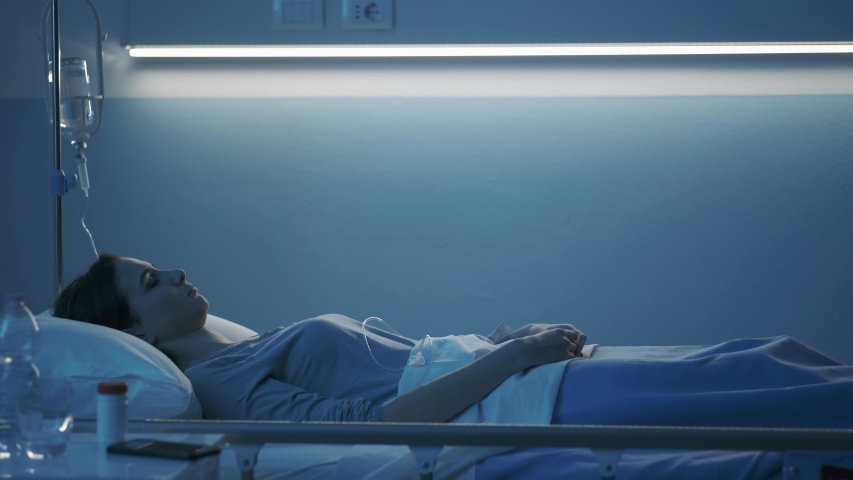 Female patient sleeping in a hospital bed at night, her soul leaves her body and goes away, near death experience concept Royalty-Free Stock Footage #1044058915
