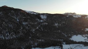 Drone video in 4k of an orange color golden sunset at the Austrian snow peaked mountains in nature