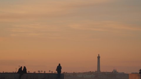 Casablanca, Morocco - 11 December 2019 : silhouettes of people at sunset in front of the lighthouse in Hassan II mosque square 