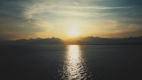Amaizing sunset sea landscape. Dramatic dark sunny water with sun path on surface, cloudy peaceful sky, silhouettes of mountaines at horizone line. Turkey, Antalya. Slow motion full hd video footage.