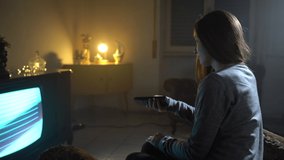 Smiling girl and dusk atmosphere in room, woman watching old-fashioned TV, changing channels, entertainment show concept. Old and new technologies, influence on people generations. Conceptual retro