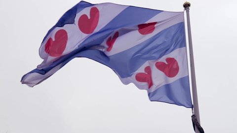 The flag of Friesland blowing on a cold grey day
