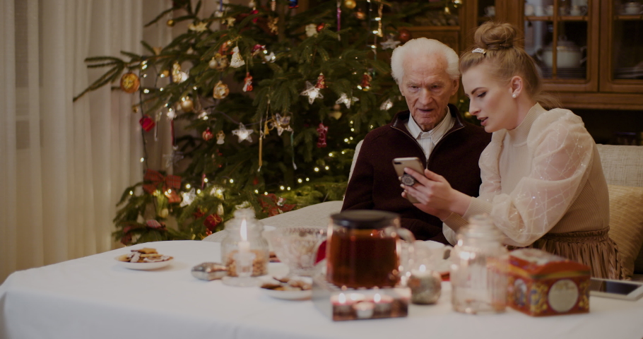 Woman Teaching Grandfather To Use Cellphone In Christmas