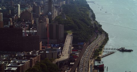 Aerial view of Manhattan greenery and skyscrapers next to river in New York during the day under overcast blue sky. Wide shot on 4K RED camera.