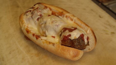 Closeup Of Cheese Meatball Sub Sandwich Being Cut With Knife.