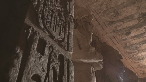 Shot of the first hall of Abu Simbel with a statue of Osiris and a column with hieroglyphics