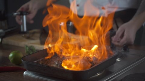 Chef making steak fillet mignon in flambe style on a grill pan. Oil and alcohol fire with open flames. Food on cuisine. Nutrition in gourmet kitchen. Making meal. Prepare food to eat. Delicious dish.