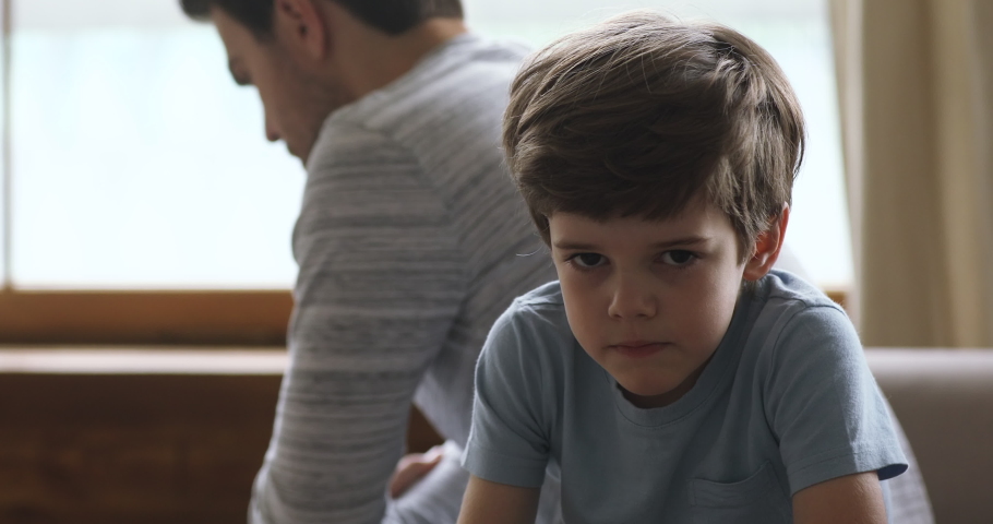 Sad preschool kid son sulking thinking of family conflicts sit turn back to unhappy dad, punished scolded little upset guilty child boy stubborn behavior in bad relationship with father concept | Shutterstock HD Video #1044100459