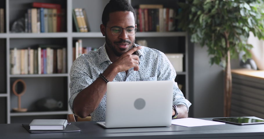 Happy african man student worker make notes study work on laptop, young male professional watch educational video webinar course distance e learn with online teacher concept sit at home office desk Royalty-Free Stock Footage #1044100558