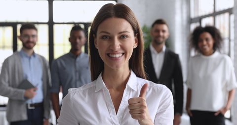 Smiling attractive young female business leader look at camera show thumbs up, happy businesswoman professional manager executive proud satisfied with career in corporate office, closeup portrait