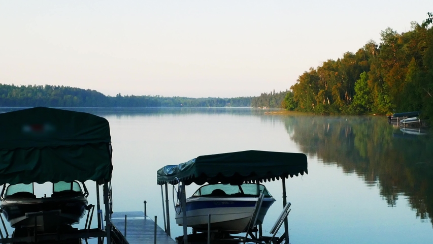 Beautiful Minnesota Lake with pleasure boats on lifts in early morning. Calm waters with reflection of shoreline.