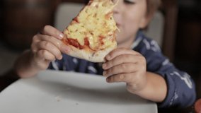 Close up of little cute boy eating pizza. Neutral colors for collor correction.