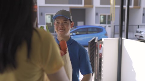 Delivery man sending vegetable healthy food order comes to customer at front house the open doorway, Delivery package service his smiling happy. Shot on 4K UHD Footage cinematic