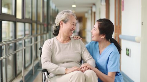 friendly asian nursing home employee talking to senior woman resident happy and smiling