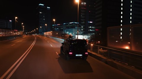 Bucharest, Romania - 10.20.2019: Crane rolling shot of a Mercedes G Klasse luxury SUV car driving on a city street at night 
