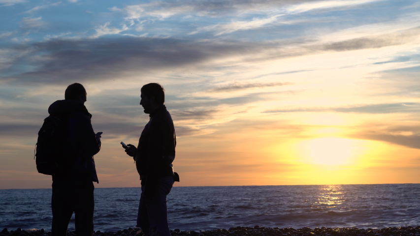 A man is photographed at sunset near the sea.