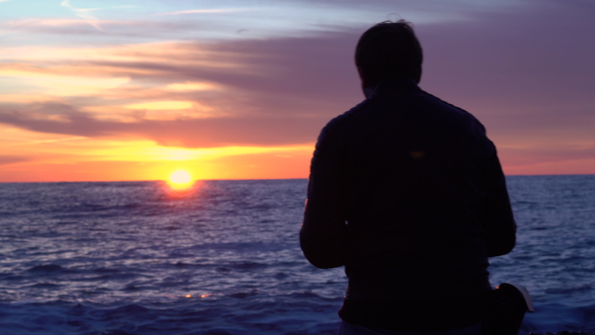 A man admires the sunset near the sea.