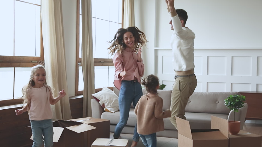 Happy new home owners tenants renters young parents and cute little children daughters dancing in living room with boxes on moving day celebrate relocation and family mortgage concept, slow motion | Shutterstock HD Video #1044147346
