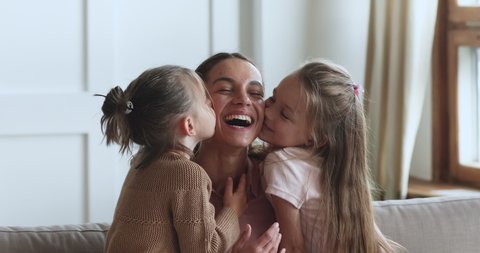 Two small cute daughters hugging kissing happy mama on cheeks, small adorable little children siblings congratulating laughing mum with mothers day bonding embrace cuddle express family love concept