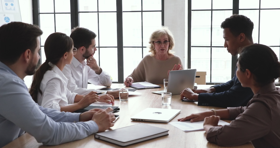 Serious mature senior company ceo talk at diverse group board meeting explain professional management strategy contract benefits to clients corporate plan financial report at conference office table Royalty-Free Stock Footage #1044147457