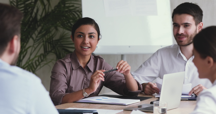 Young female professional indian leader manager teaching corporate staff discussing project with diverse team coworkers working together in teamwork share ideas sit at group office meeting table | Shutterstock HD Video #1044147460