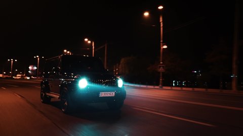 Bucharest, Romania - 10.20.2019: Crane rolling shot of a Mercedes G Klasse luxury SUV car driving on a city street at night 