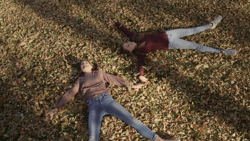 High angle view of girls laying in autumn leaves making angel / Cedar Hills, Utah, United States