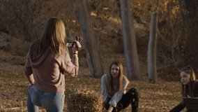 Girl recording playful friends throwing autumn leaves at each other / Cedar Hills, Utah, United States