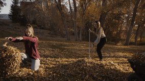 Playful girls throwing autumn leaves at each other / Cedar Hills, Utah, United States