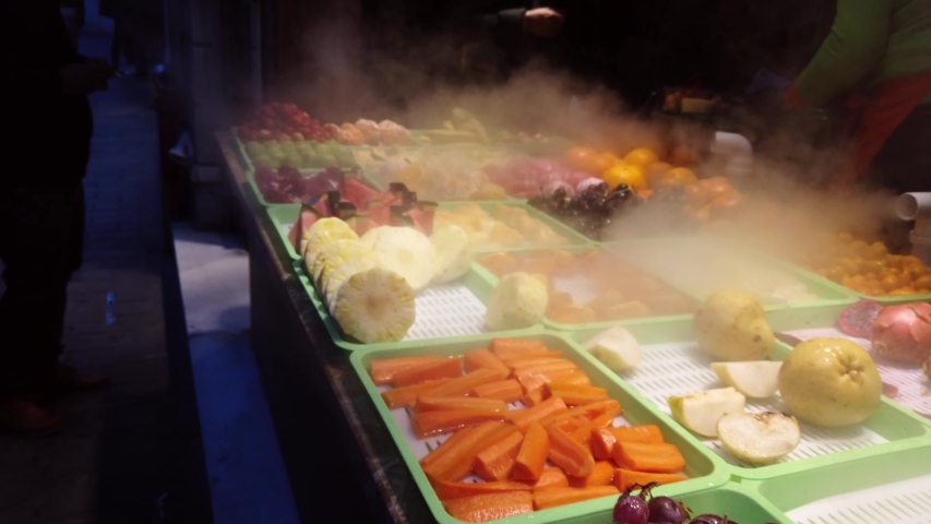 Sliced fruits like grapes, pear, carrot, orange, mandarin, kumquat are selling in a store at The Istiklal Street, Istanbul. Fruits look very fresh when moistened with steam.