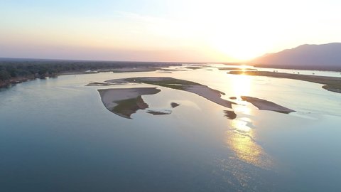 Aerial footage of a huge Zambezi river and nature from above during sunset, mirroring on water surface. West view, Mana Pools national park landscape, Zimbabwe, Africa.