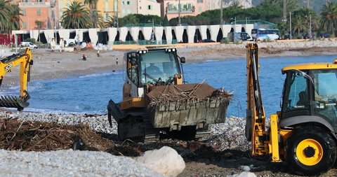 Menton, France - January 6, 2020: Three Yellow Bulldozers (JCB And Liebherr) Cleaning Debris On The Beach After A Storm In Menton, France, French Riviera, Europe. Close Up View - DCi 4K Resolution