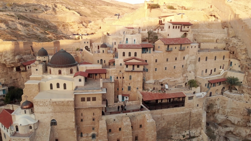 Aerial view of an ancient greek monastery located in Judean desert in Israel on a cliff, fly over with camera facing down, smooth motion, 4k