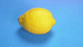 ripe yellow lemon painted pink with spray paint on a blue background.