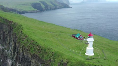 Aerial view of lighthouse at Mykines island in Faroe Islands, North Atlantic Ocean. Made by drone from above. Nordic natural landscape.